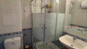 Ein Badezimmer mit Duschkabine, Toilette und Waschbecken.