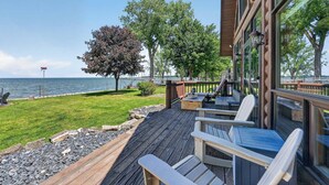 A deck with outdoor seating, a view of the water, and a tree. - Gorgeous log home in Southern Door- Waterfront retreat (Luxemburg)