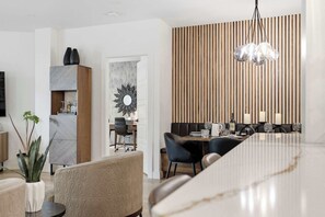 Un comedor moderno con una mesa larga, sillas y una pared decorativa con listones verticales de madera.