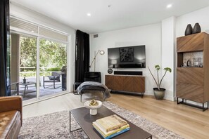 Una sala de estar moderna con una televisión de pantalla plana, un sofá, una mesa de centro y una estantería.