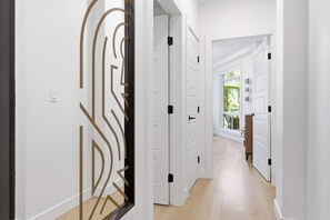 Een hal met witte deuren, een licht houten vloer en een decoratief wandpaneel.