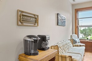 A cozy living area with a coffee maker, a framed sign reading 'COFFEE BAR', and a window with a view. - The Urban Botanist-Botanical Garden/ZOO/The Grove/Tower Grove Park (St. Louis)