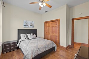 A bedroom with a bed, a nightstand, a ceiling fan, a wooden door, and a painting on the wall. - The Urban Botanist-Botanical Garden/ZOO/The Grove/Tower Grove Park (St. Louis)
