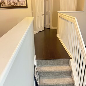 Eine Treppe mit dunklem Holzboden und weißen Geländern, die zu einer Tür mit weißem Rahmen führt.