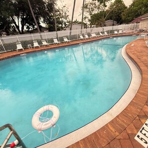Una piscina con un flotador salvavidas, rodeada por una valla blanca y sillas de descanso.