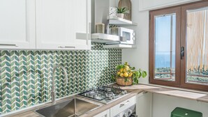 A kitchen with a gas stove, a sink, cabinets, a microwave, and a window with a view. - Concettina Apartment sea view for up to 5 people! (Massa Lubrense)