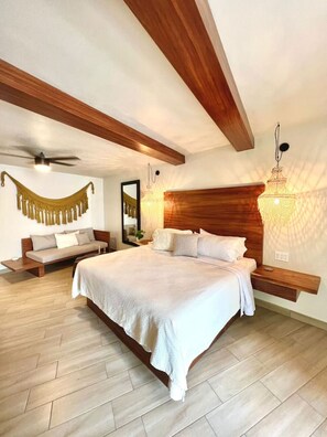 Un dormitorio con una cama grande, vigas de madera, un colgante de luz e integrado un banco.