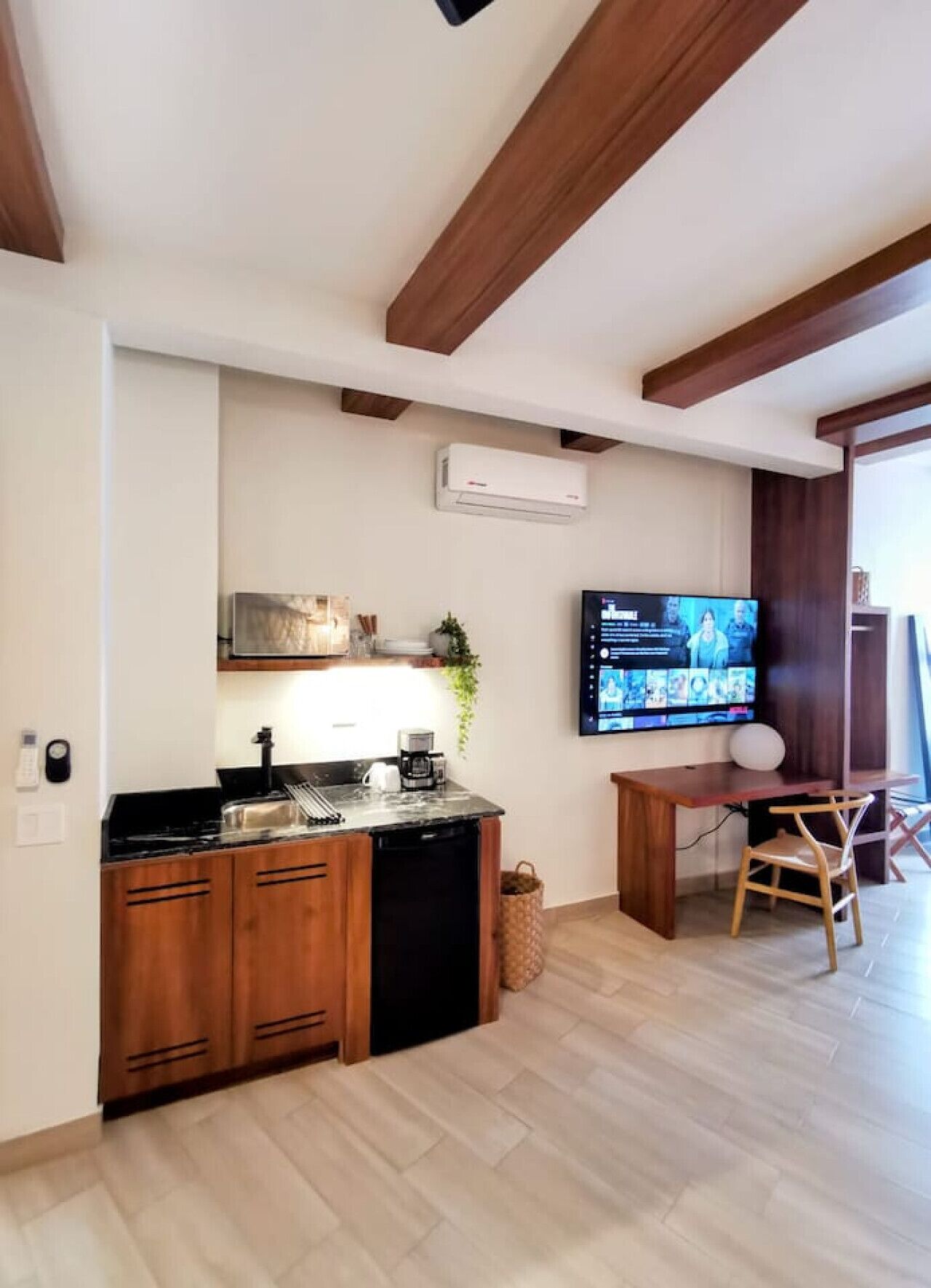 A modern kitchen with wooden cabinets, a black countertop, and an air conditioning unit.