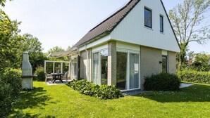 Et moderne hus med skråt tag, store glasvinduer og en velplejet have.