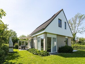 Ein modernes Haus mit Satteldach, großen Glasfenstern und einem gepflegten Garten.