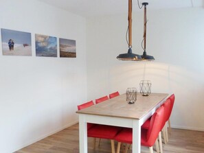 Ein Essbereich mit einem Holztisch, rot gepolsterten Stühlen und einer Pendelleuchte.
