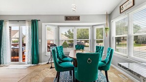 Un comedor con sillas color turquesa, una mesa y vistas a través de amplios ventanales.