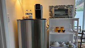 A kitchen with a stainless steel refrigerator, a microwave, a water dispenser, and a wall-mounted light fixture. - Cozy studio, independent entrance, with AC in vibrant Orlando neighborhood (Orlando)