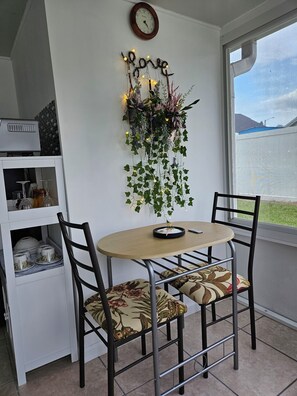 A dining area with a round table, two chairs, a wall-mounted clock, and a decorative hanging with lights and plants. - Cozy studio, independent entrance, with AC in vibrant Orlando neighborhood (Orlando)
