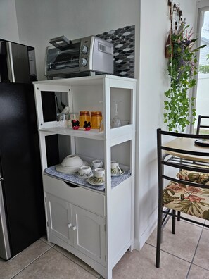 Une petite cuisine équipée d’un four à micro-ondes, d’un grille-pain et de placards de rangement.