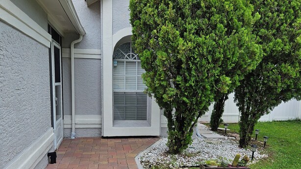 A house with a paved walkway, a small garden with shrubs, and a window with a metal grill. - Cozy studio, independent entrance, with AC in vibrant Orlando neighborhood (Orlando)