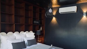 A hotel room with a bed, a wall-mounted air conditioner, a shelf with a 'Music & Dance' sign, and a bedside lamp. - 'Casa Maramar' – with Wi-Fi and Air Conditioning (Angra do Heroísmo)