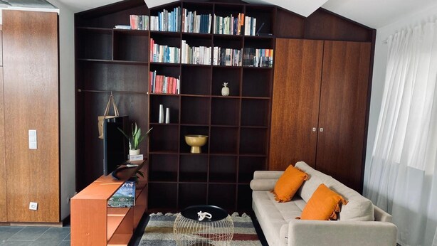 A modern living room with a bookshelf, a sofa, a coffee table, and a TV stand. - 'Casa Maramar' – with Wi-Fi and Air Conditioning (Angra do Heroísmo)