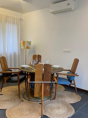 A dining area with a round table, wooden chairs, and woven mats on the floor.