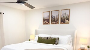 A bedroom with a bed, a ceiling fan, a nightstand, a lamp, and three framed pictures on the wall. - The Olive Mesa - HotTub - Fire pit - Sandbox (Lubbock)