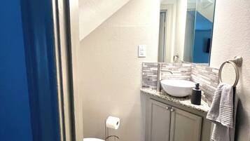 Une salle de bain équipée de toilettes, d’un lavabo, d’un miroir et d’un porte-serviettes.
