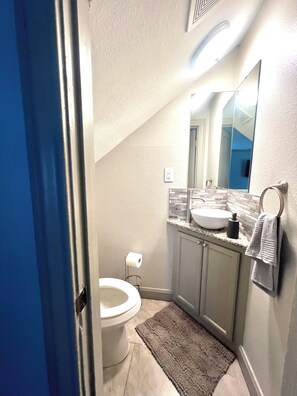 A bathroom with a toilet, sink, mirror, and towel rack. - Cozy Graceful 2BR Near Downtown Houston (Houston)