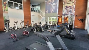 Une salle de sport équipée de tapis de course, de vélos d’appartement et d’appareils de musculation.