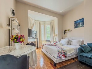 Habitación de hotel con una cama, un escritorio, una silla, una mesa con flores y un sofá azul.