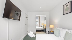 Ein Hotelzimmer mit Bett, Fernseher, Nachttischlampe und Spiegel.