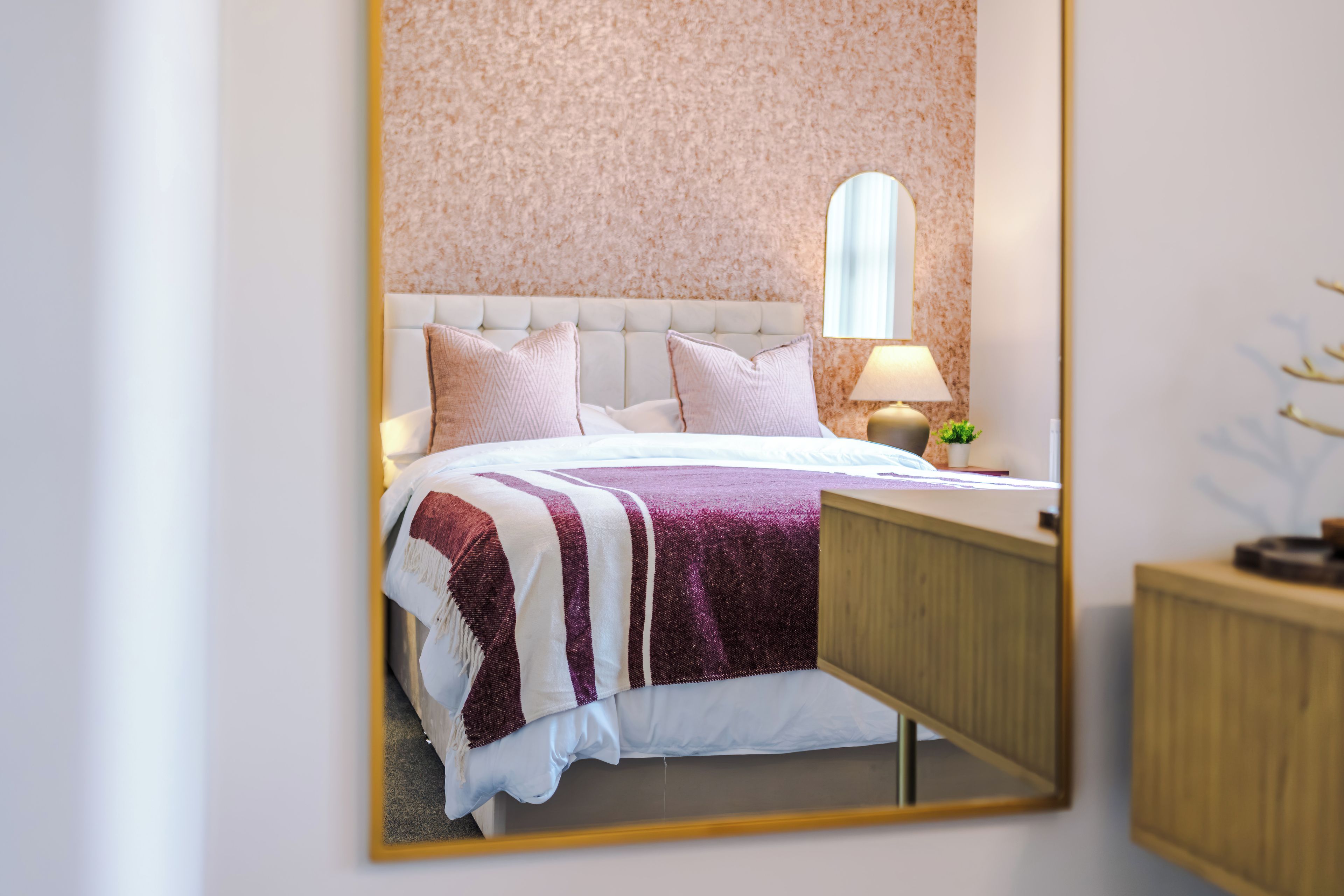 Ein Schlafzimmer mit einem Bett, Kissen, einem Nachttisch und einer Lampe.