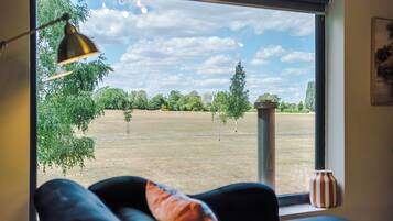 Ein Zimmer mit großem Fenster, einer schwarzen Couch, einer Lampe und einer Vase.
