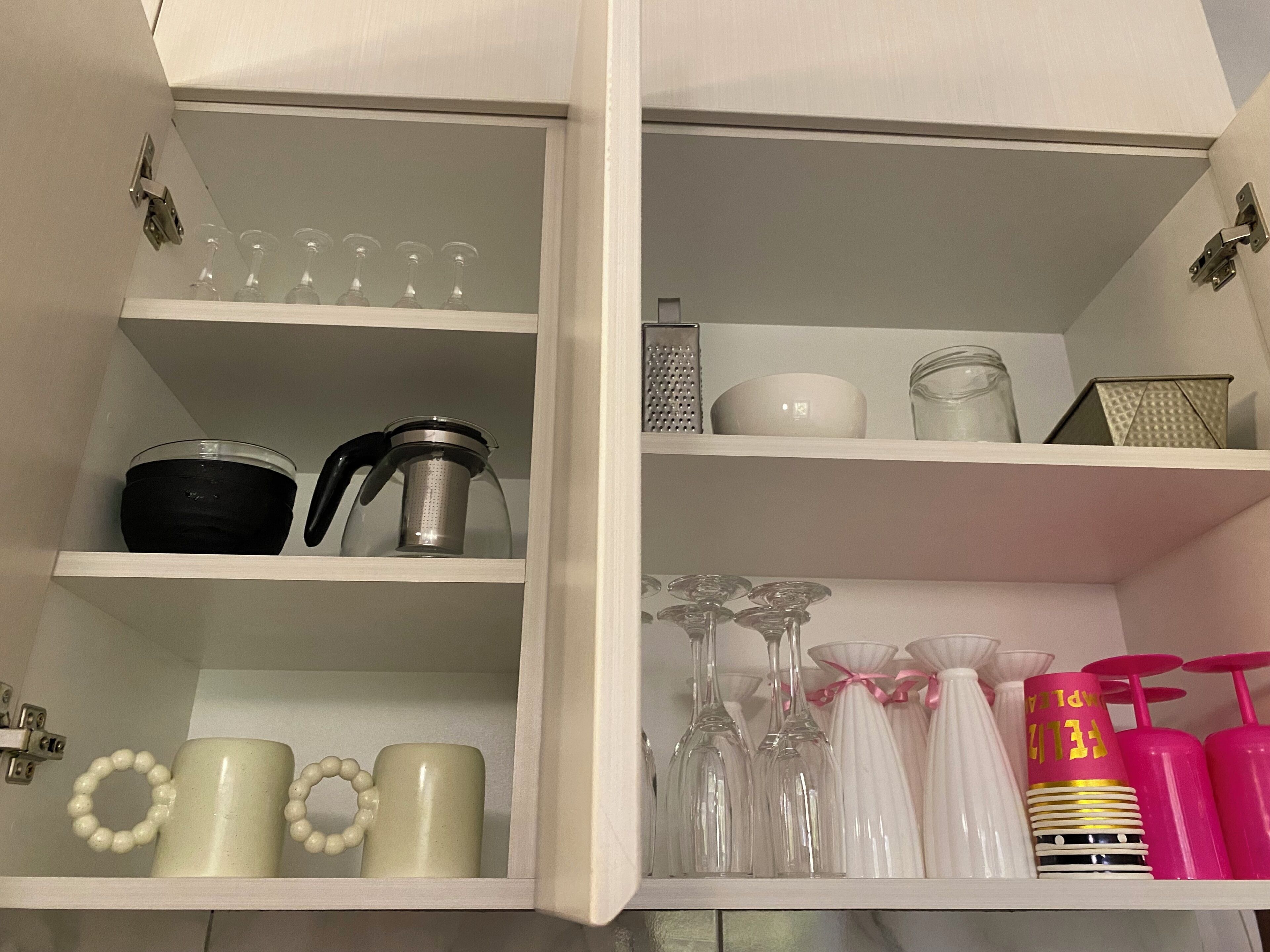 Een keuken met planken vol keukengerei, waaronder een koffiezetapparaat, een rasp en een pot.