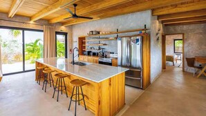 Une cuisine moderne dotée d’un grand îlot central, de tabourets de bar et d’un réfrigérateur en acier inoxydable.