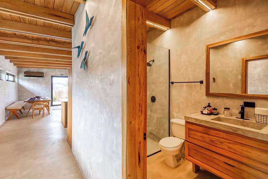 A modern bathroom with a wooden vanity, a shower, and a large mirror.