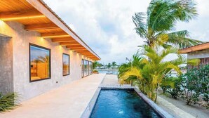Un bâtiment moderne doté d’une piscine, de grandes fenêtres et de plantes tropicales.