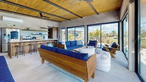 Een modern interieur met een houten plafond, een keukenhoek en grote ramen met uitzicht op de omgeving.