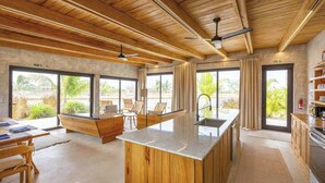 Une cuisine moderne avec des meubles en bois, un îlot central et de grandes fenêtres.