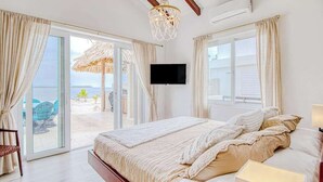 Une chambre à coucher avec un lit, des rideaux, une télévision et une vue sur la plage.