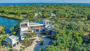 Ein modernes, mehrgeschossiges Haus mit Pool, umgeben von üppiger Vegetation und Blick auf den Ozean.