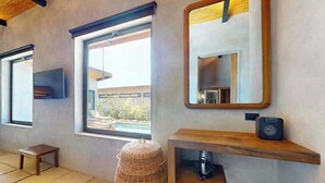 A modern bathroom with a large window, a mirror, a wooden shelf with a speaker, and a small stool. - Elegant waterfront villa with private terrace, pool, beach access & 4 en-suites (Placencia)