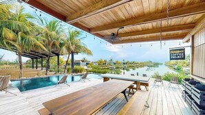 Eine Holzterrasse mit Pool, Liegestühlen und einem Tisch.