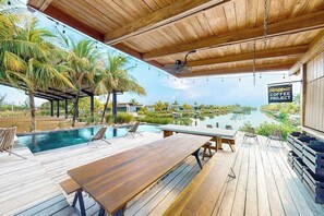 Eine Holzterrasse mit Pool, Liegestühlen und einem Tisch.