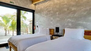 A hotel room with two beds, a window with a view of palm trees, and a door marked 'EXIT'. - Tranquil waterfront villa with private deck & full kitchen (Placencia)