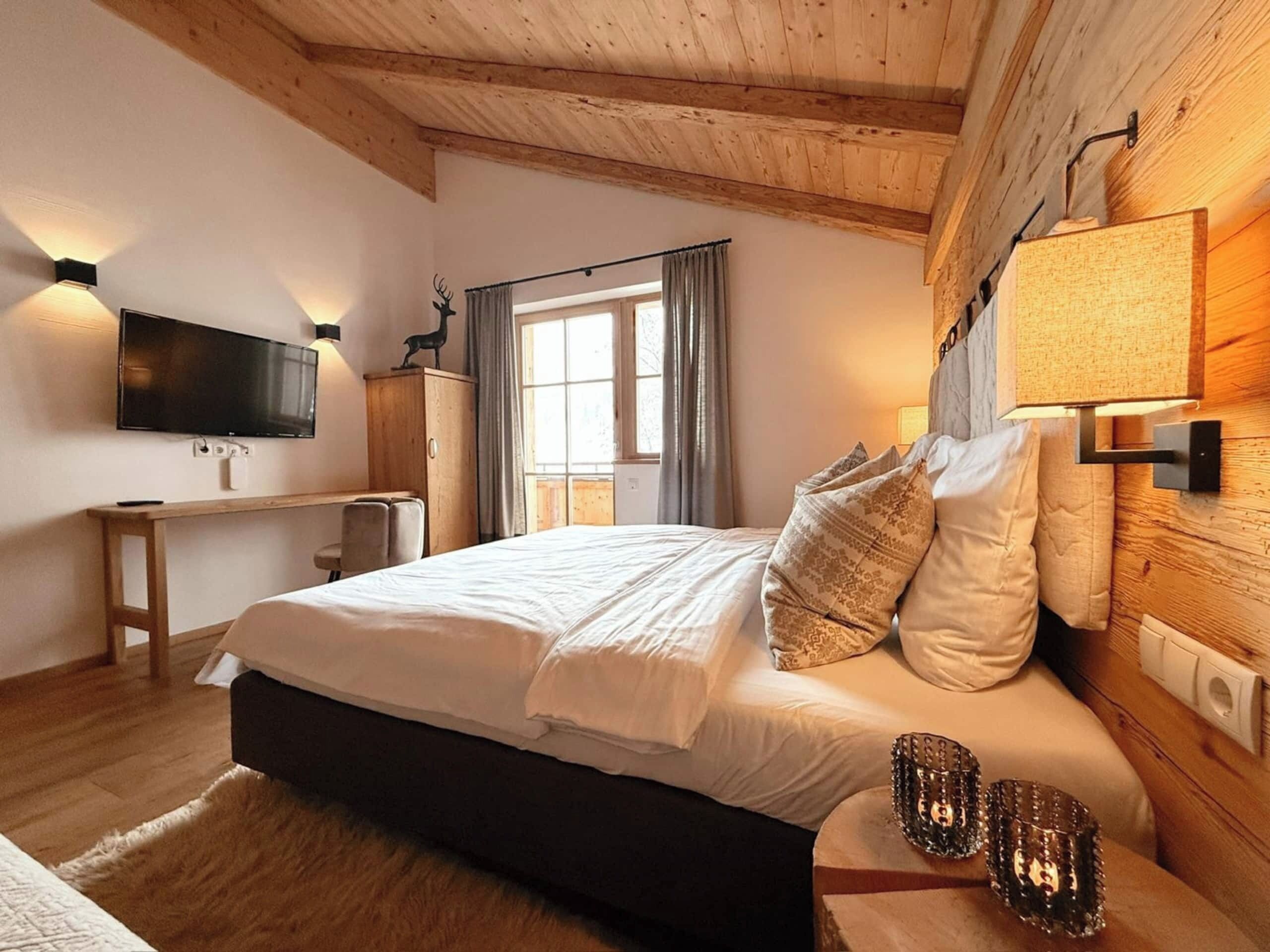 Ein Schlafzimmer mit einem Bett, einem Schreibtisch, einem Fernseher und einem Fenster mit Vorhängen.