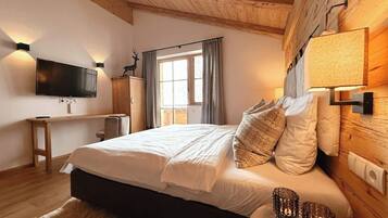 Ein Schlafzimmer mit einem Bett, einem Schreibtisch, einem Fernseher und einem Fenster mit Vorhängen.