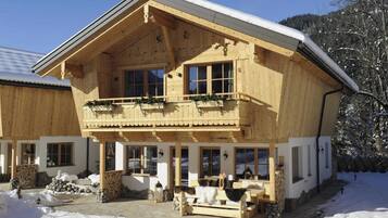Eine Holzhütte mit Balkon, großen Fenstern und einem Steinfundament.