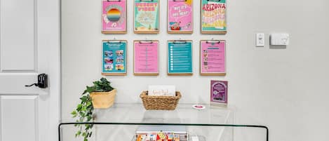 A wall with various informational posters, a guest book, a chess set, and a small plant.