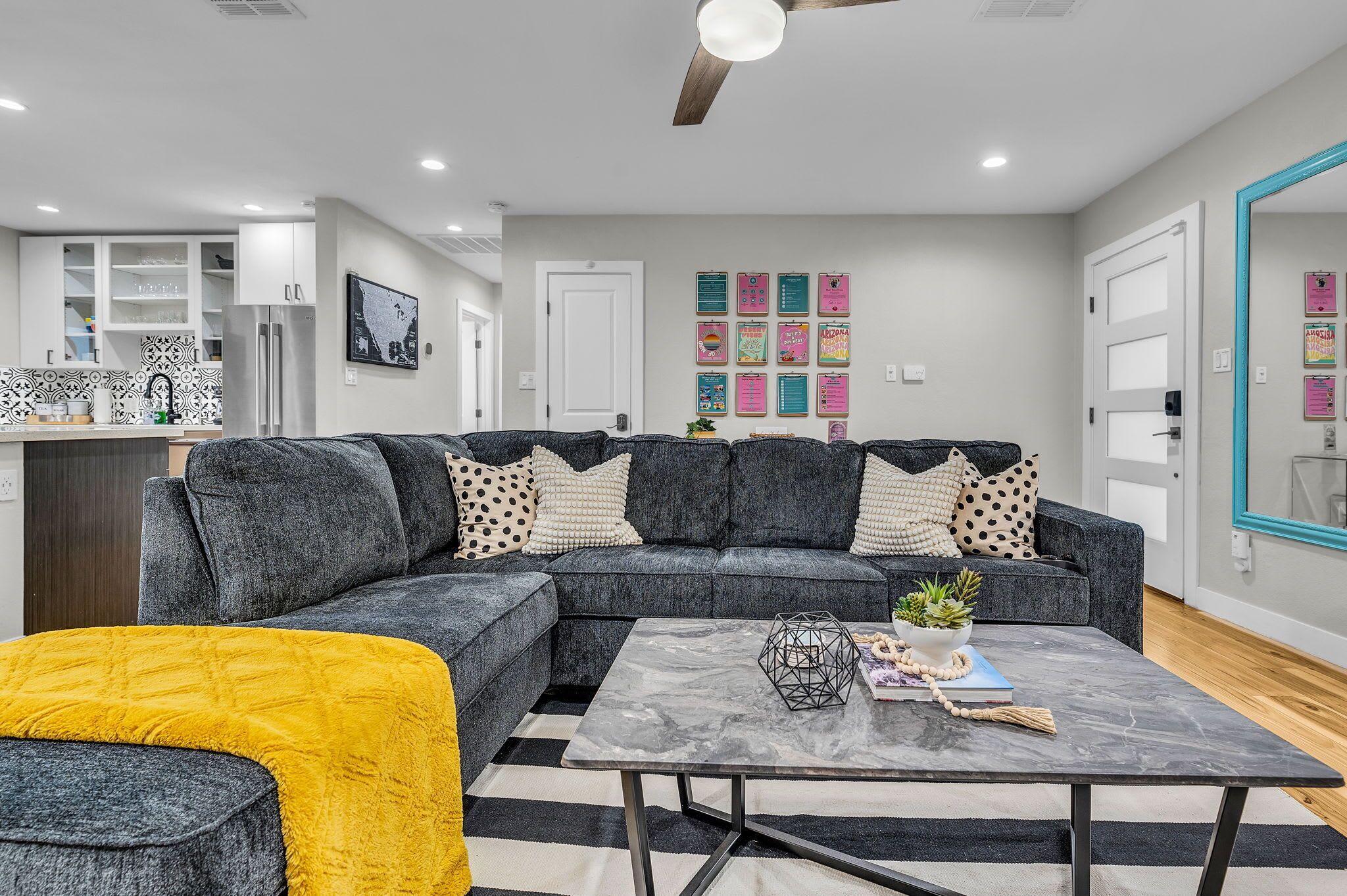 A modern living room with a sectional sofa, a coffee table, and a kitchen in the background.