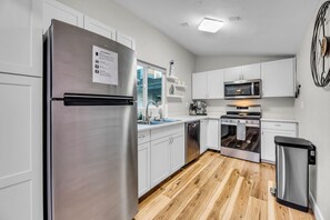 A modern kitchen with stainless steel appliances, white cabinetry, and a wooden floor. - The Poolside Club - Pool/Spa/Swim Up Bar (Phoenix)