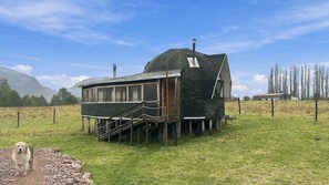 Une construction rustique en bois, dotée d’un toit à forte pente, d’une cheminée et d’un petit porche avec des marches menant à l’entrée.